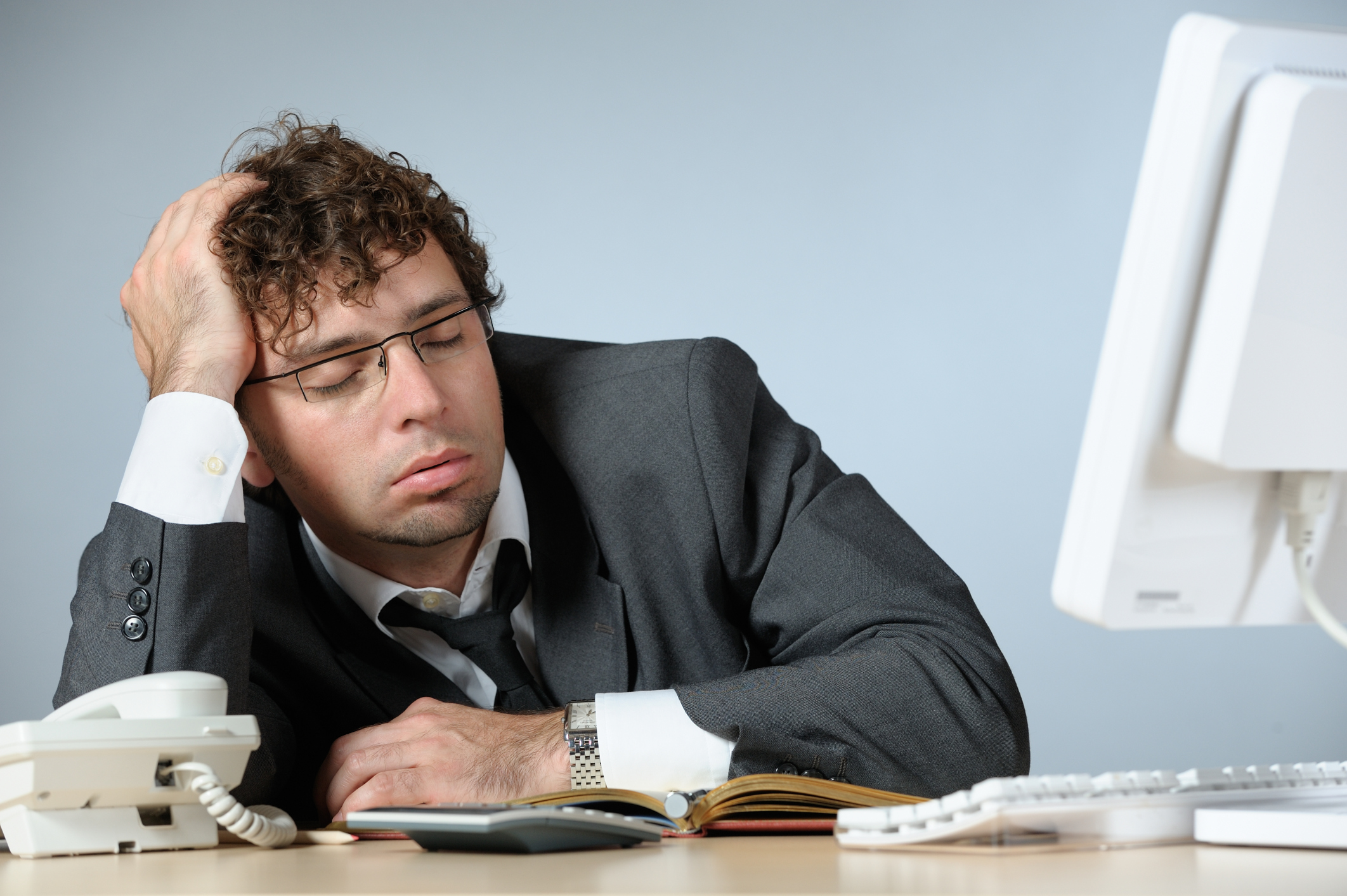 A person falling asleep at his desk.