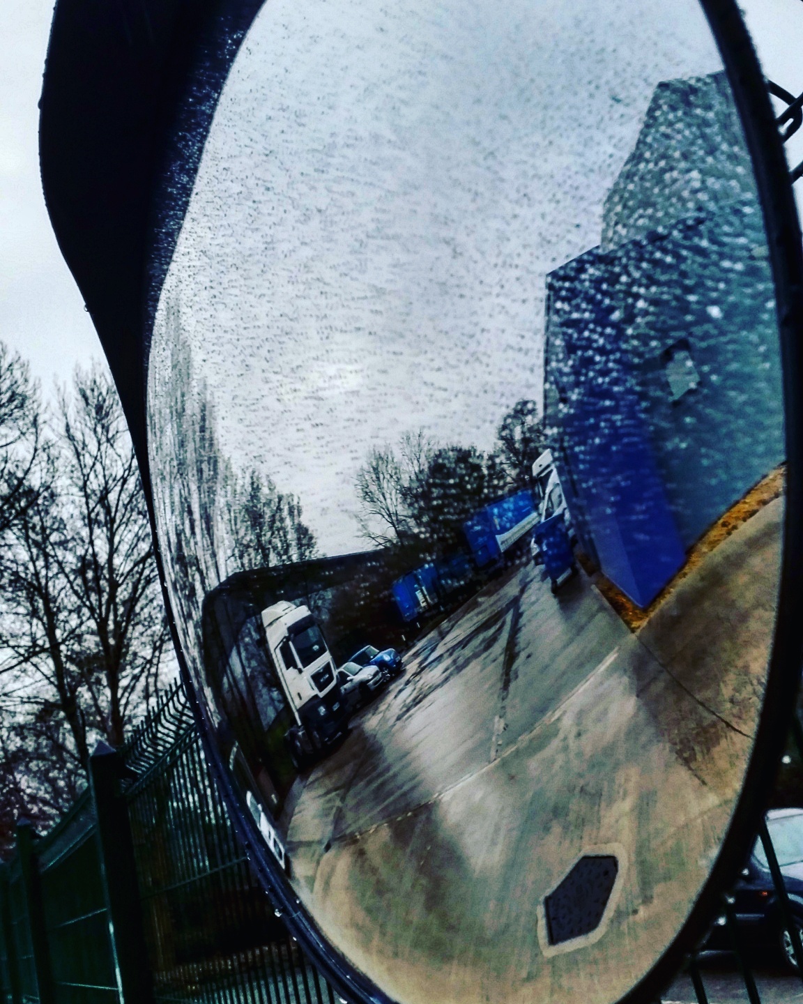 A mirror showing vehicles in a car park.
