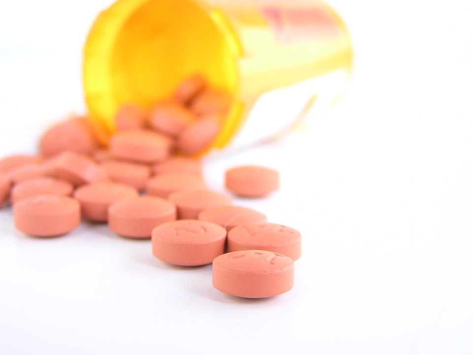 Pink pills spilled out from a pill bottle.