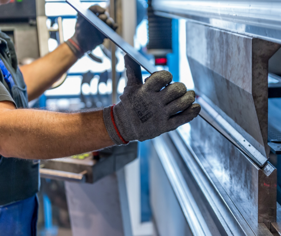 A man completing work in a factory with protective gloves on.