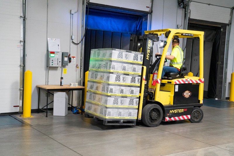 A worker driving a forklift with products on.