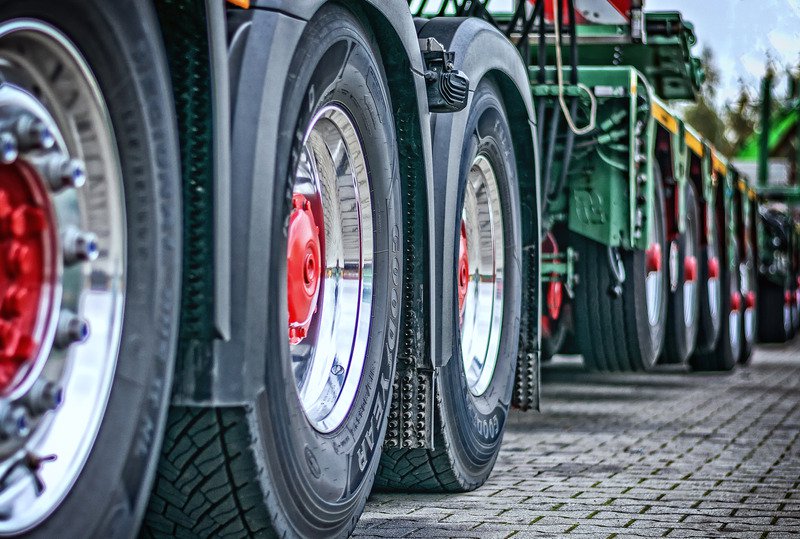 Wheels of a truck with a red centre, with another green truck behind them.