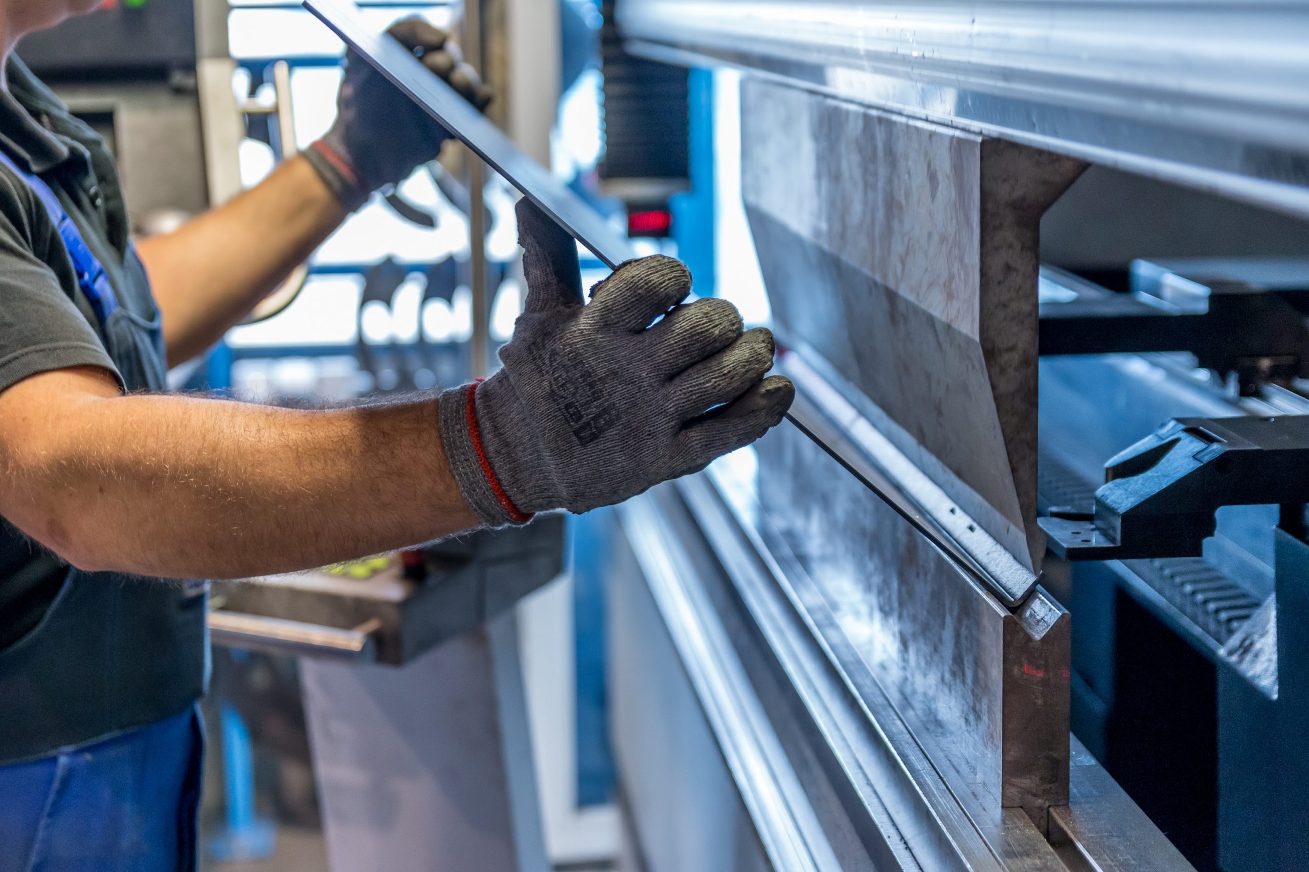 A person holding a piece of metal wearing safety gloves.