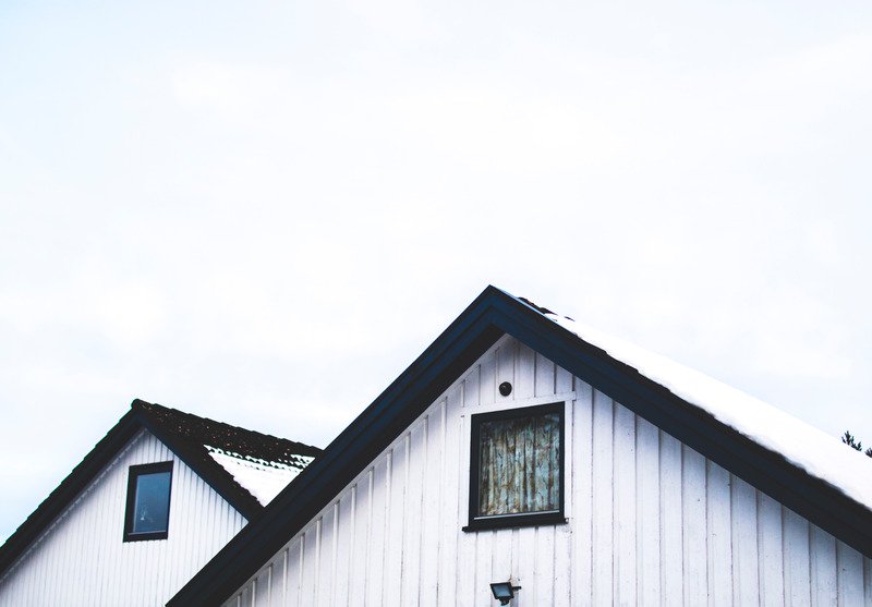Two white paneled roofs with a black trim and windows below it.