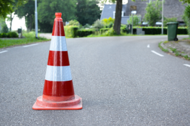A red and white striped cone on a road.
