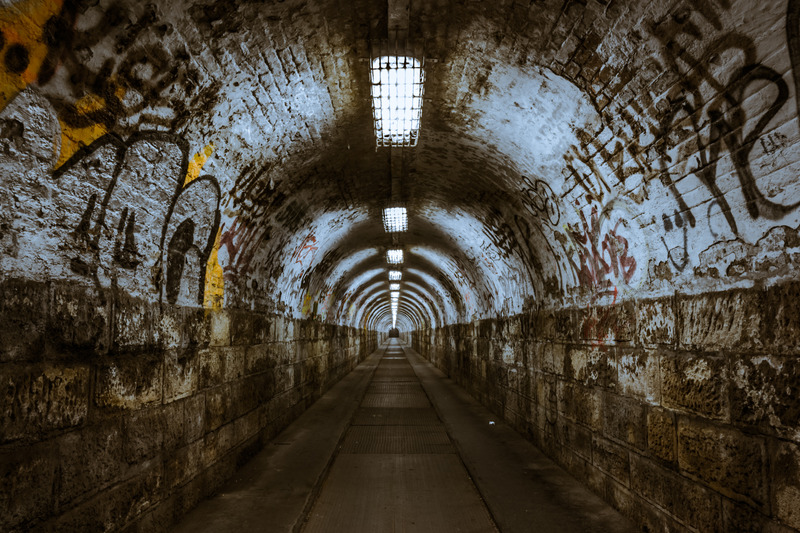 An underground tunnel that has graffiti along the walls.