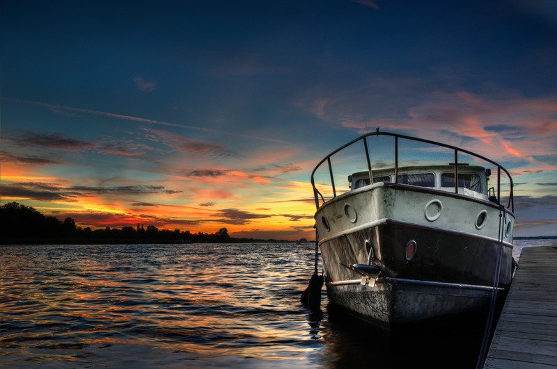 A white boat on a body of water during sunset.