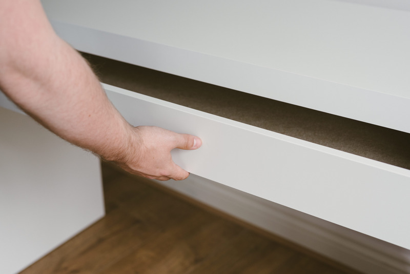 A person opening a white chest of drawers.