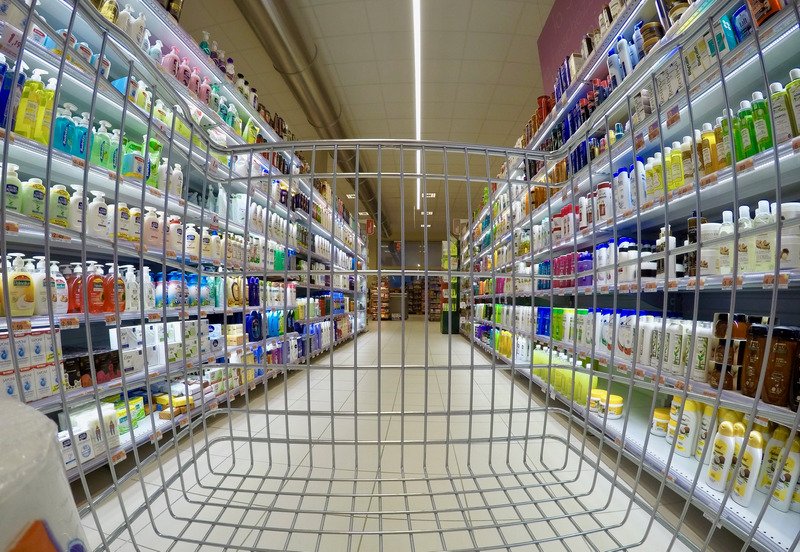 A trolley being pushed in the toiletry aisle of a supermarket.