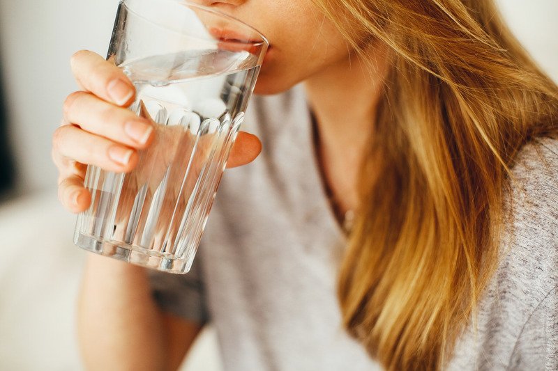 A woman with blond hair taking a drink of water.