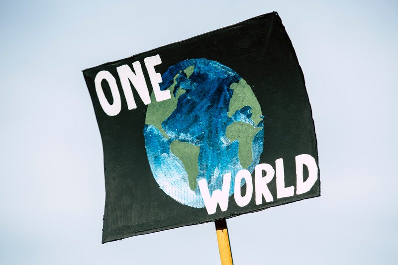 A sign with a black background then a globe and the words 'One World'.