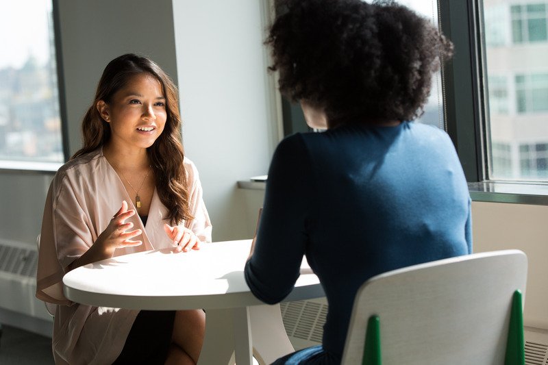 Two women sat at a table talking.
