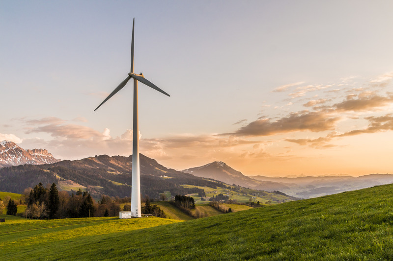 A wind turbine in a field surrounded by mountains.