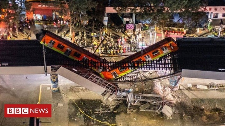 Two train carriages hanging from a collapsed metro overpass in Mexico City