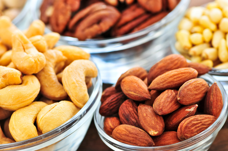 Almonds, cashews, pistachio and pine nuts in glass bowls