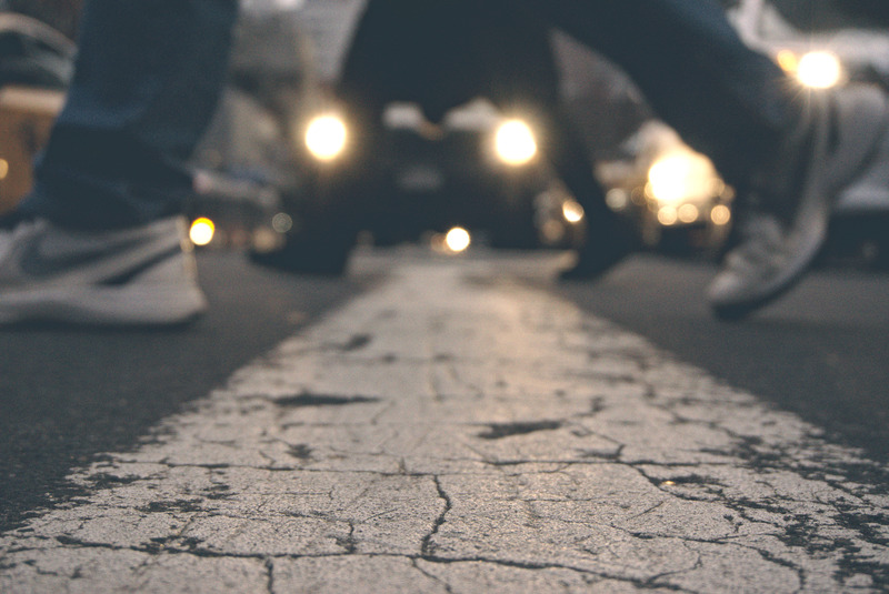 A person crossing the street by a zebra crossing.