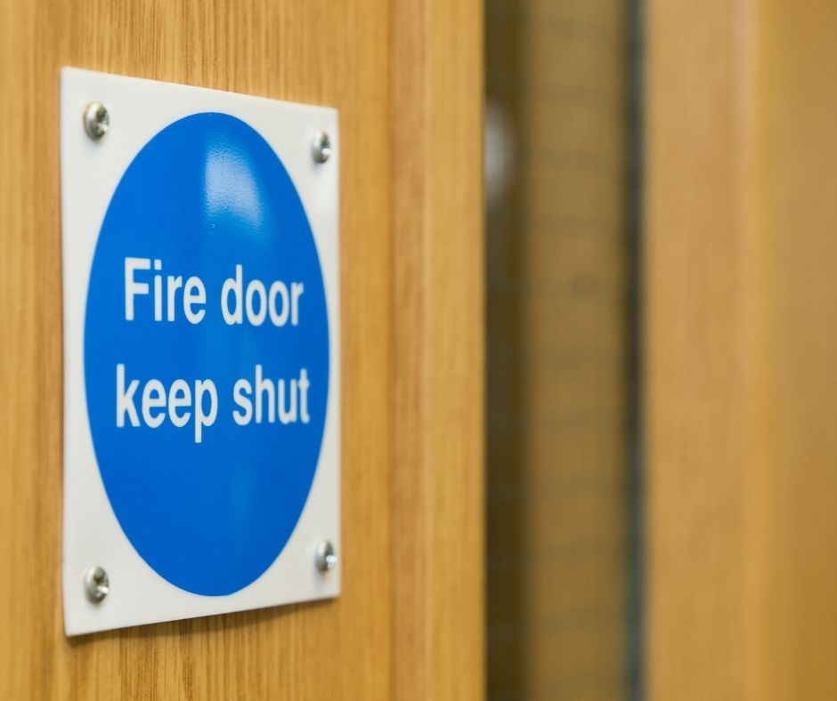 Close up of a fire door on the panel that reads 'Fire Door Keep Shut'