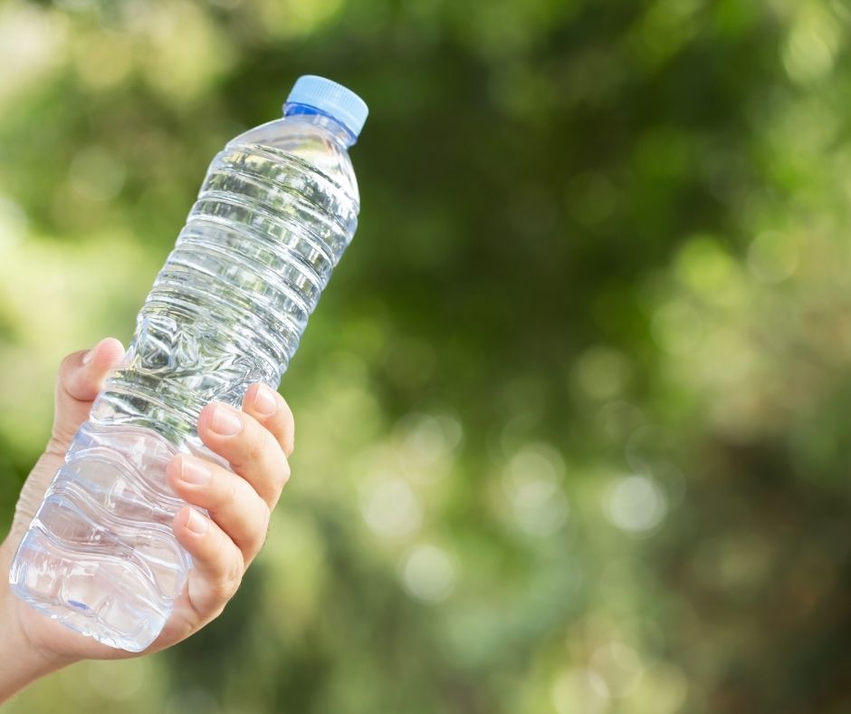 A hand holding a clear plastic bottle of water