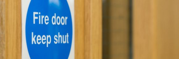 Close up of a fire door on the panel that reads 'Fire Door Keep Shut'