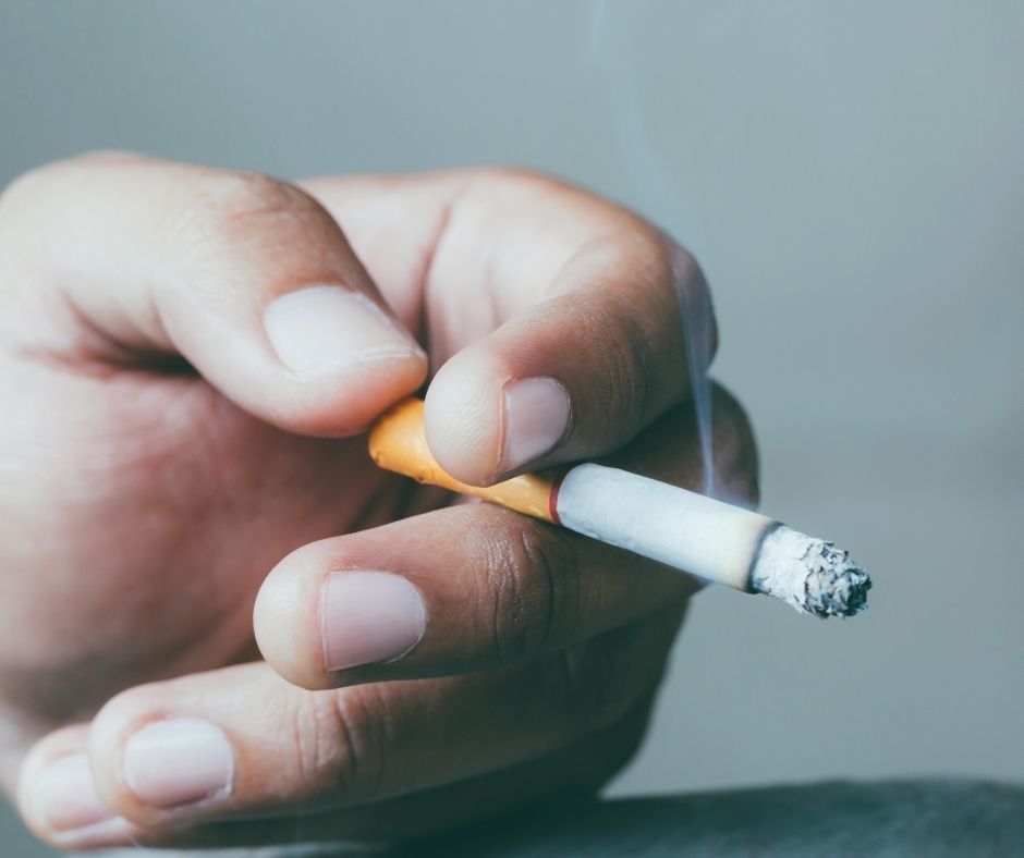 Close up of a hand holding a lit cigarette