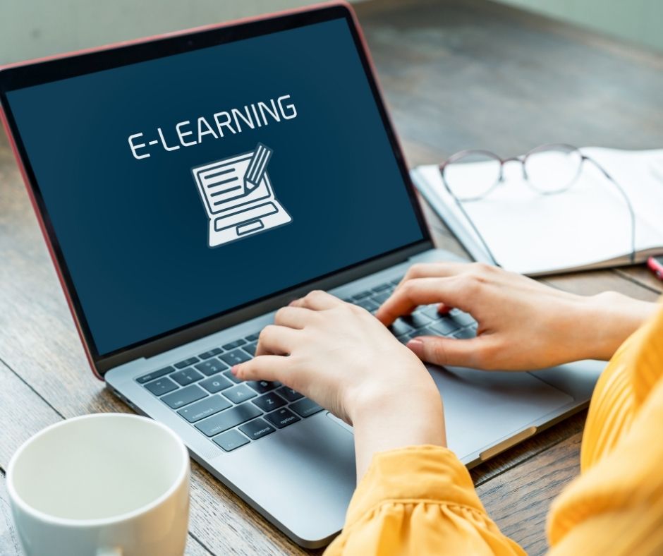 laptop with 'e-learning' on the screen, hands typing on the keyboard