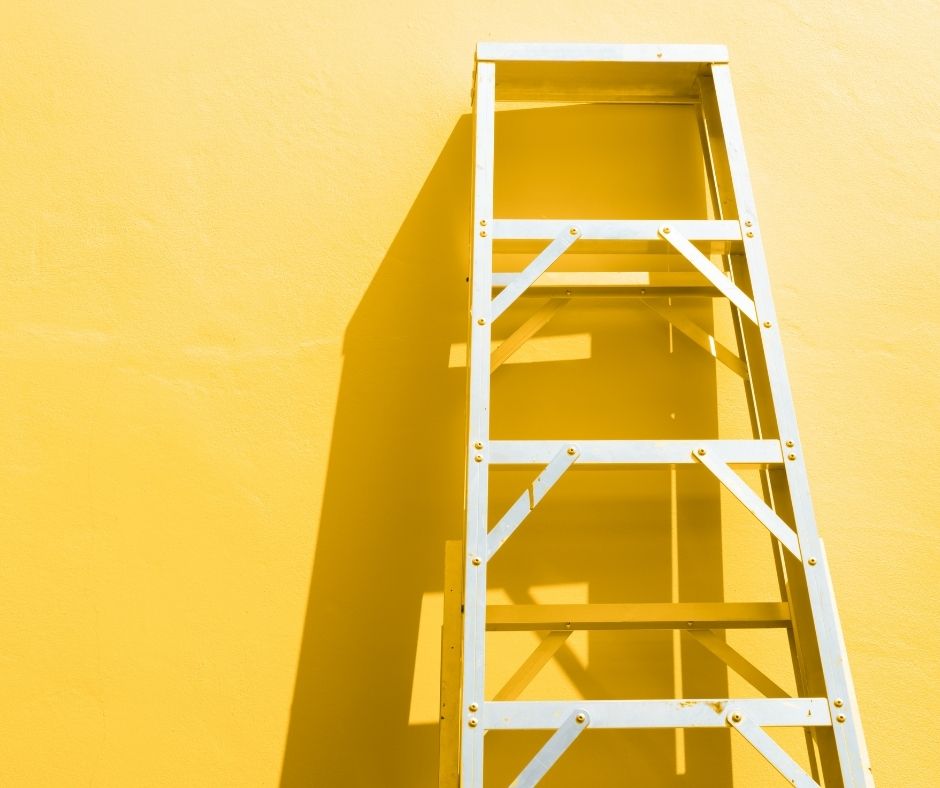 Ladder leaned against a yellow wall