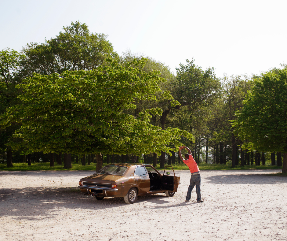 man stretching outside of car