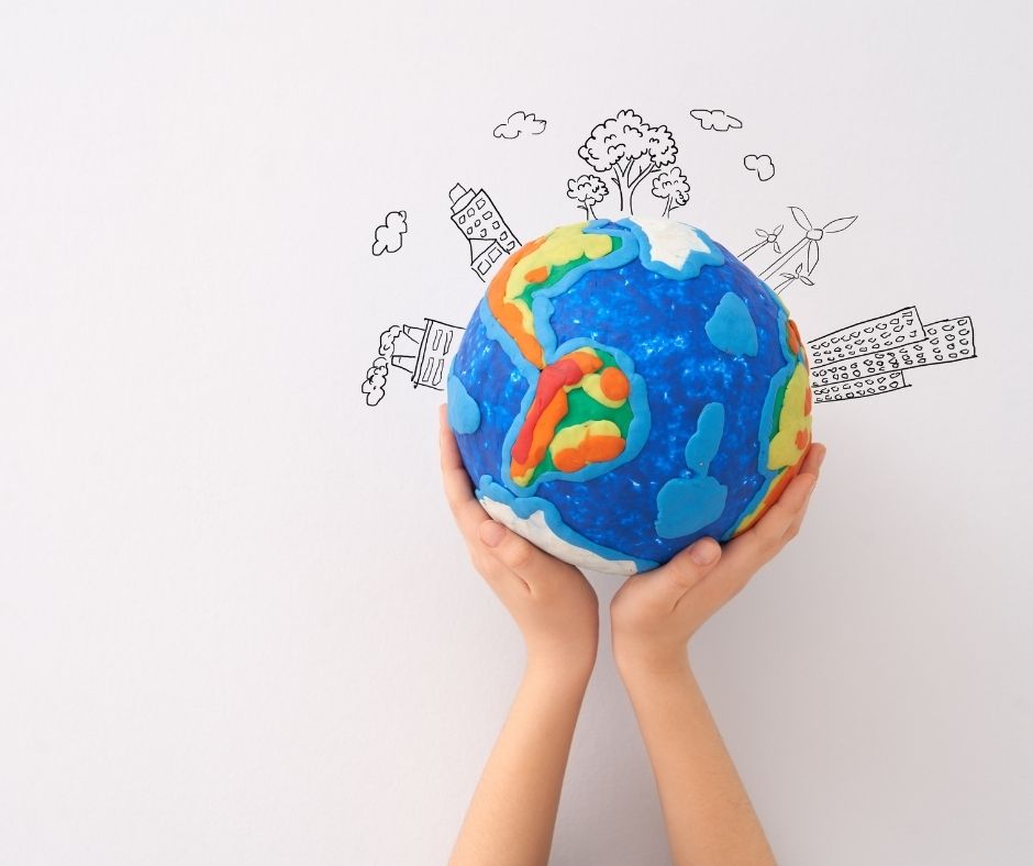 hands holding a colourful globe with drawings of buildings surrounding it