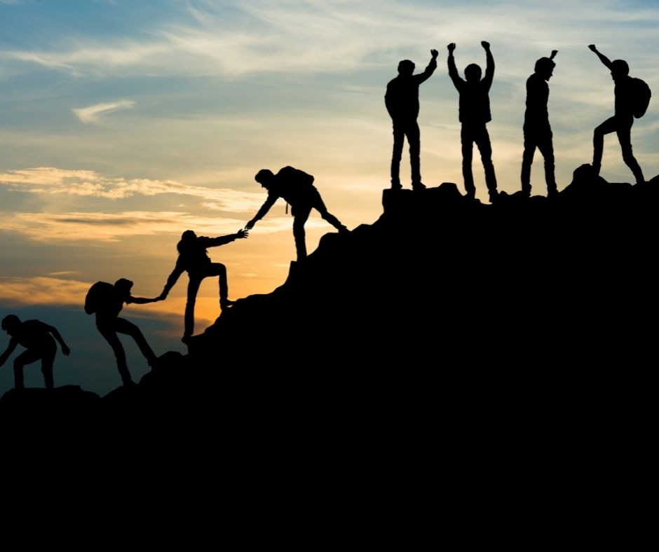 team of people climbing a mountain, helping eachother