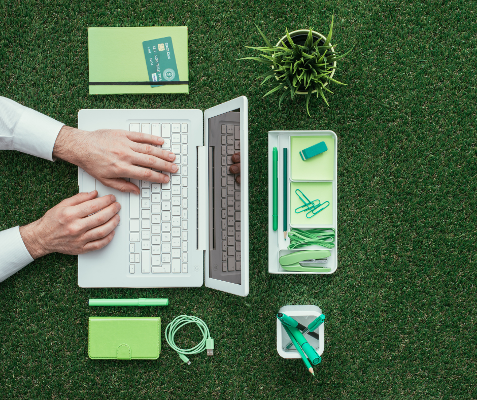Hands on laptop surrounded by green office items