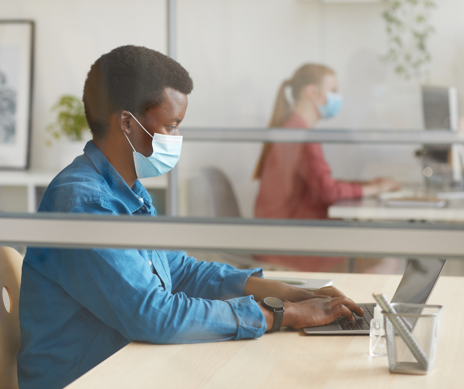Two people working in an office wearing face masks
