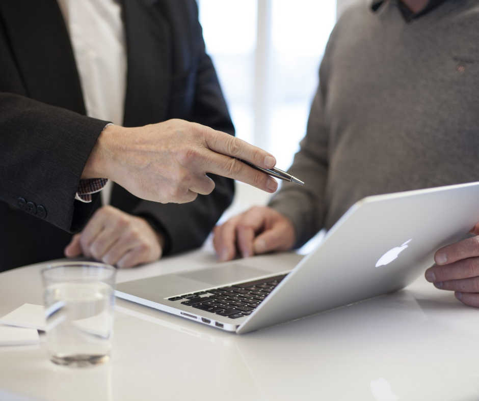 Two men having a discussion around a macbook