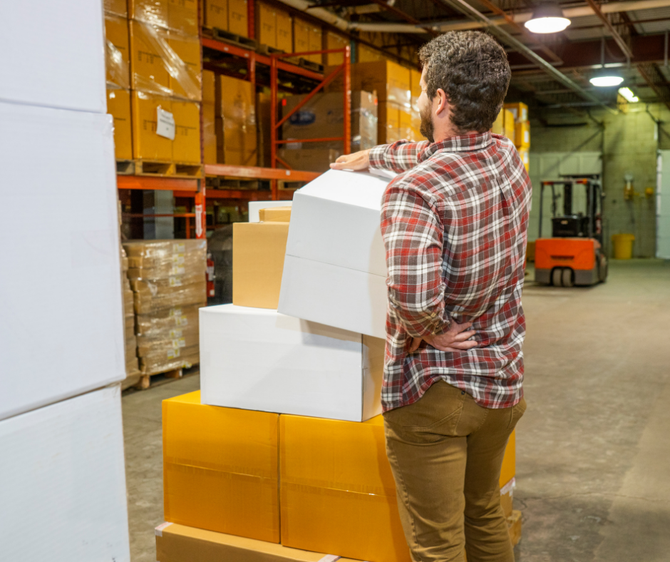 a man lifting boxes, holding his back in pain
