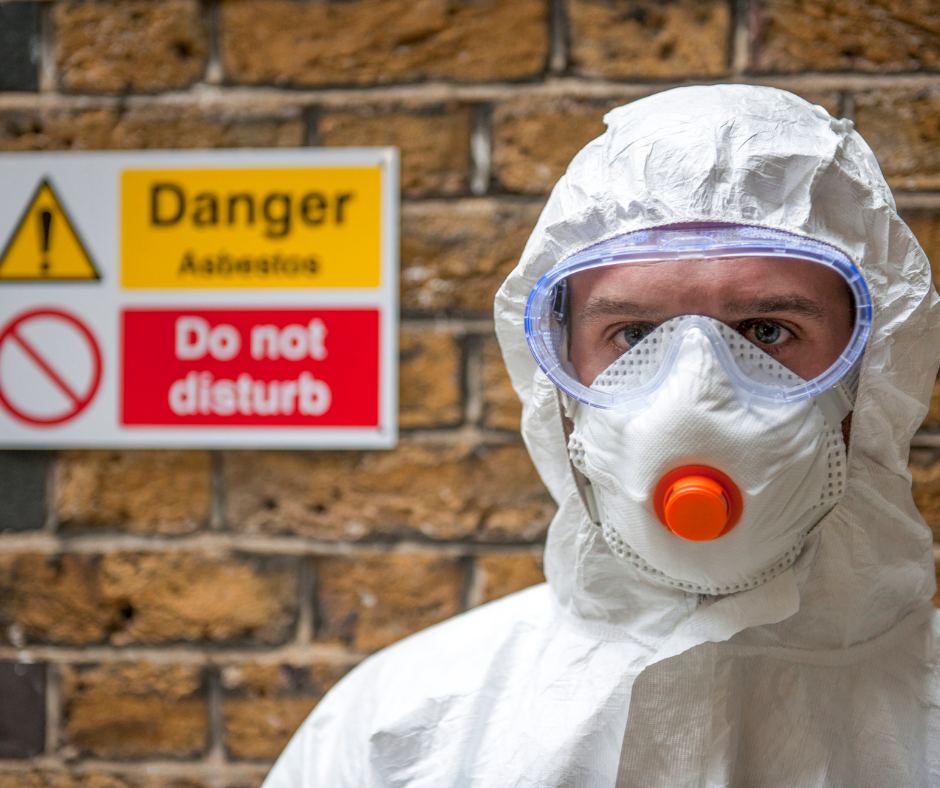 Man wearing a respiratory mask in front of an asbestos sign