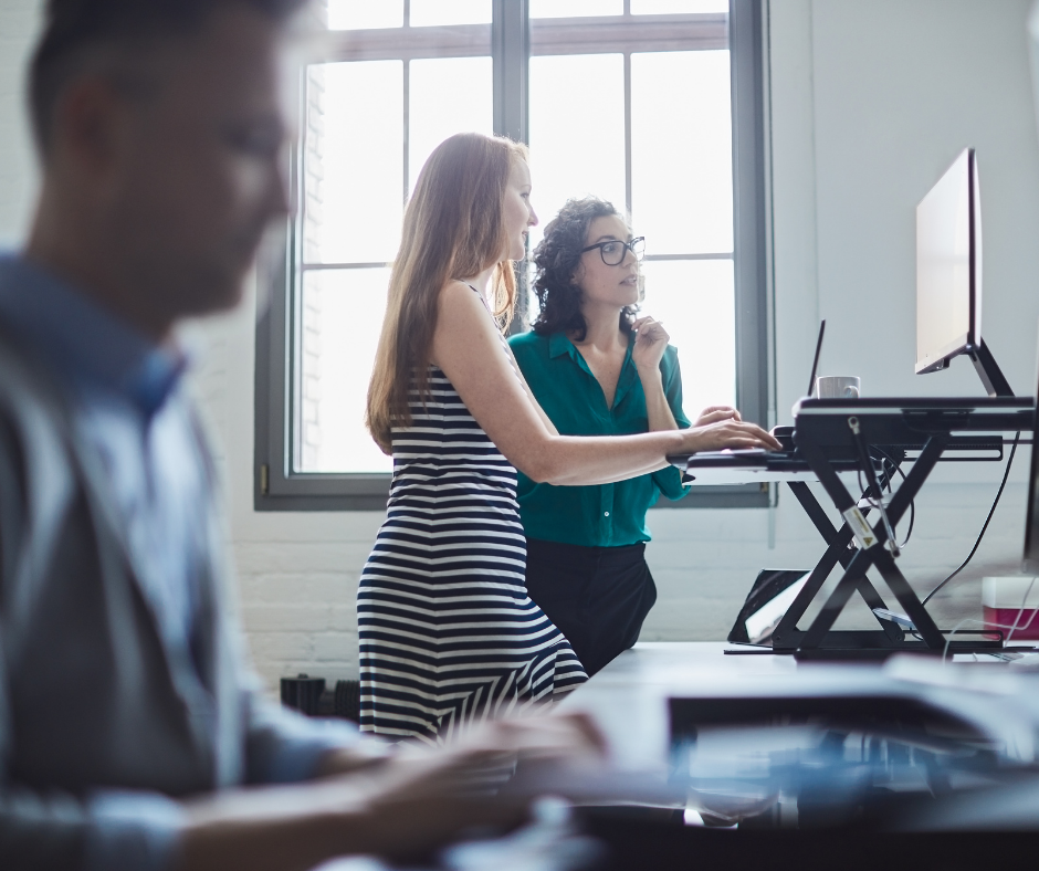 Man and two women using ergonomic desks