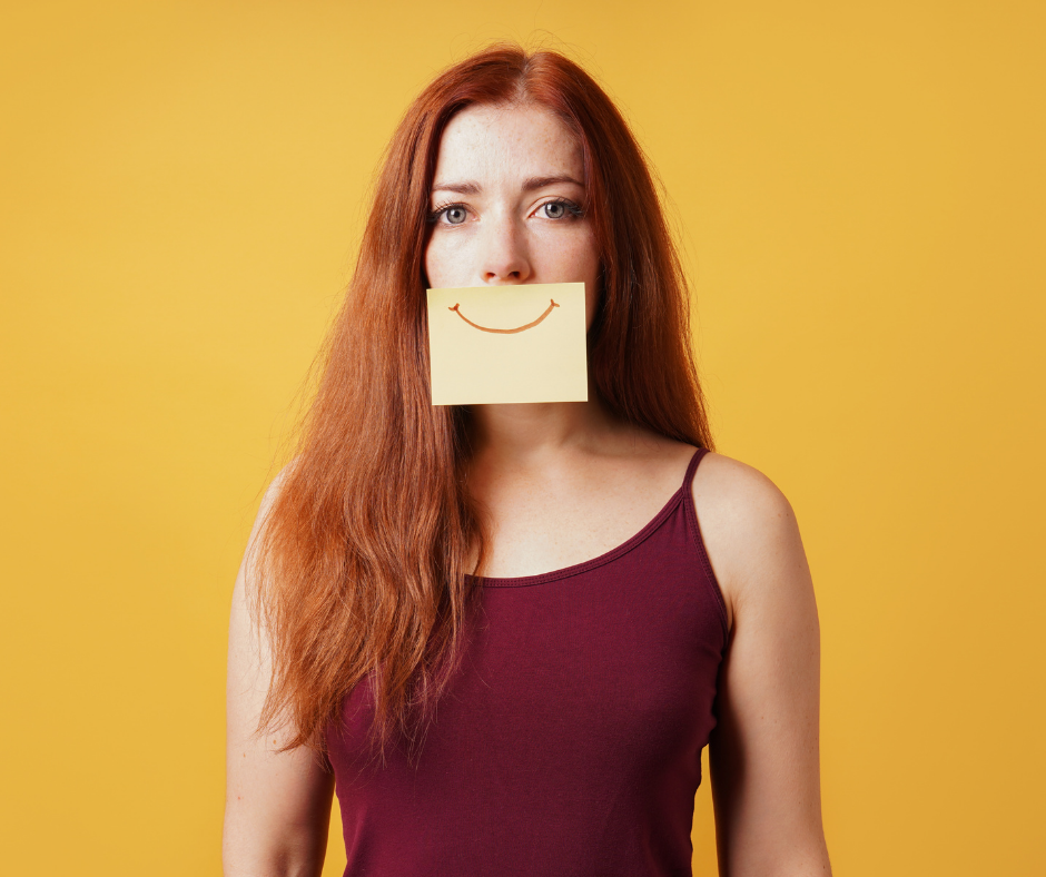 Woman with a piece of paper with a smile on it over her mouth