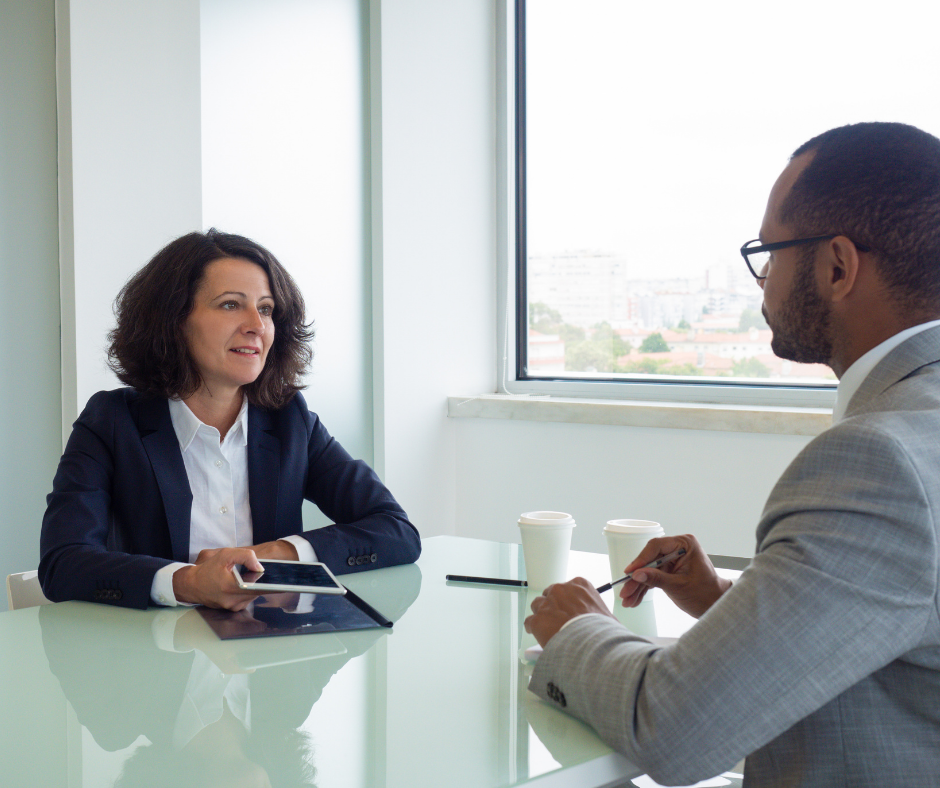 Man and woman sitting at a glass table having a meeting