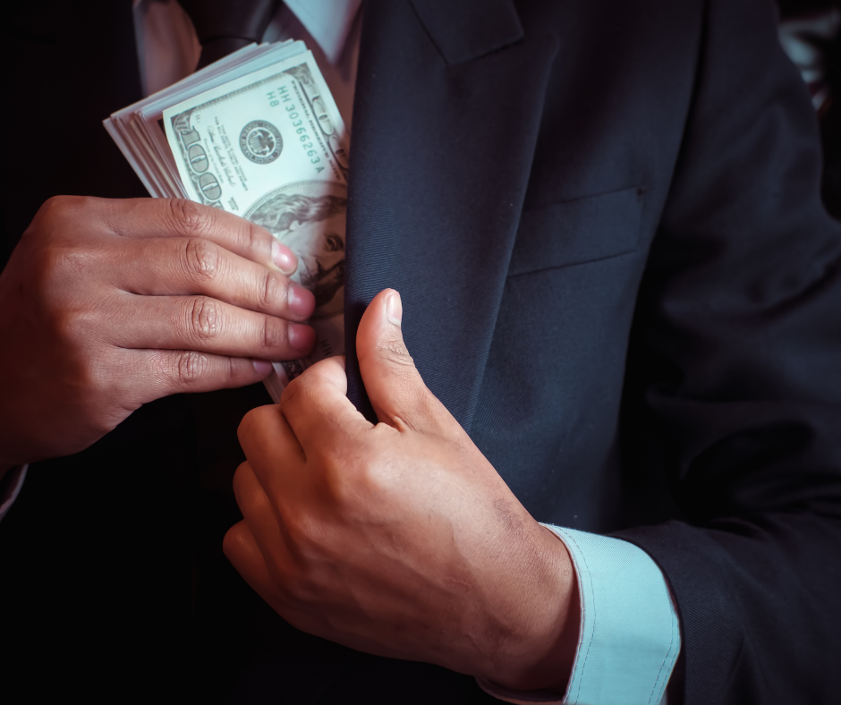 Close up of a man tucking a stack of cash into his inside jacket pocket