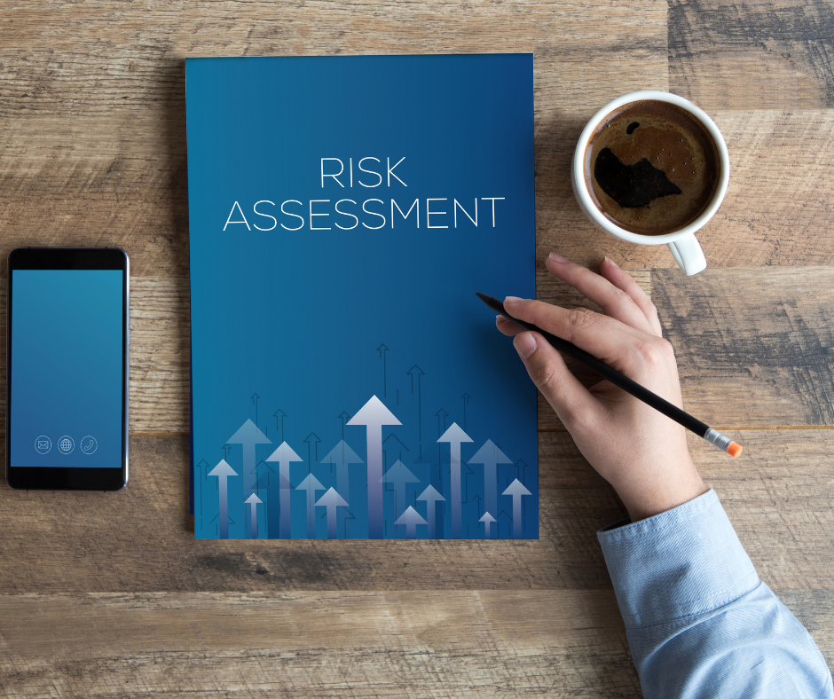 Blue document that says risk assessment on a table next to a phone and cup of coffee