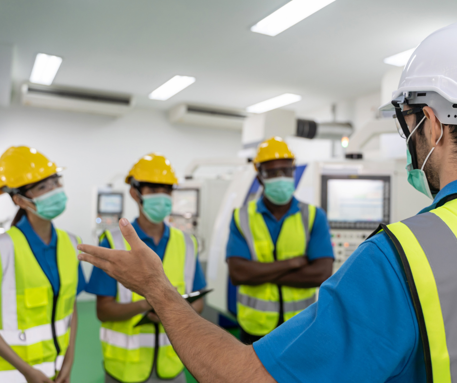 Factory workers meeting before work wearing helmets and masks
