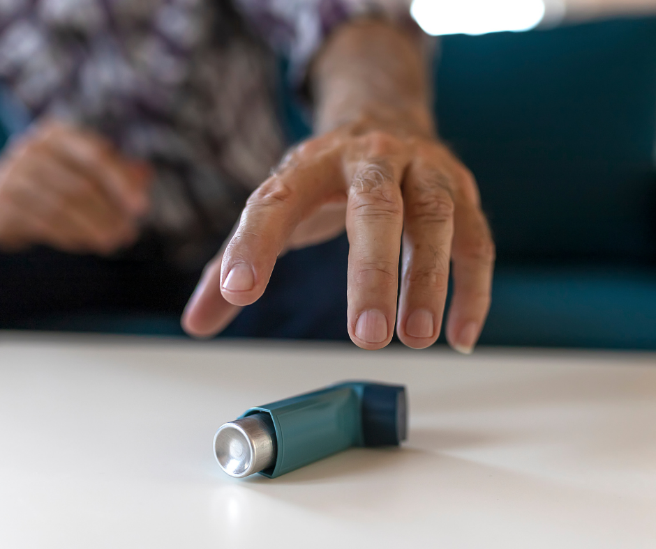 Hand reaching for a blue inhaler on a table