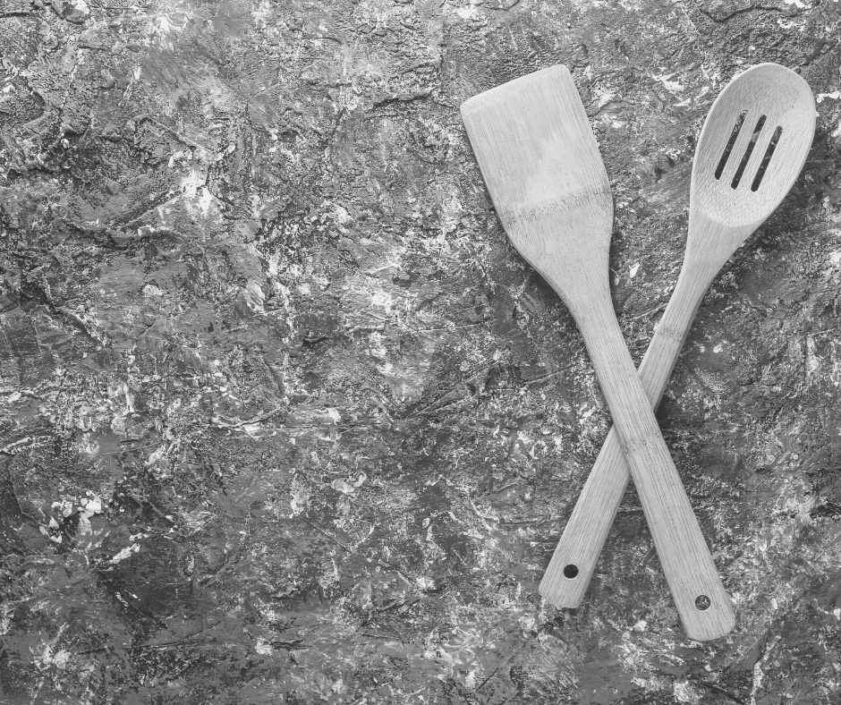 Black and white image of a wooden spatula and spoon crossed over eachother