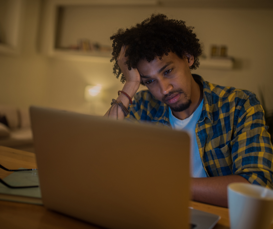 Man sitting at a laptop at home looking stressed
