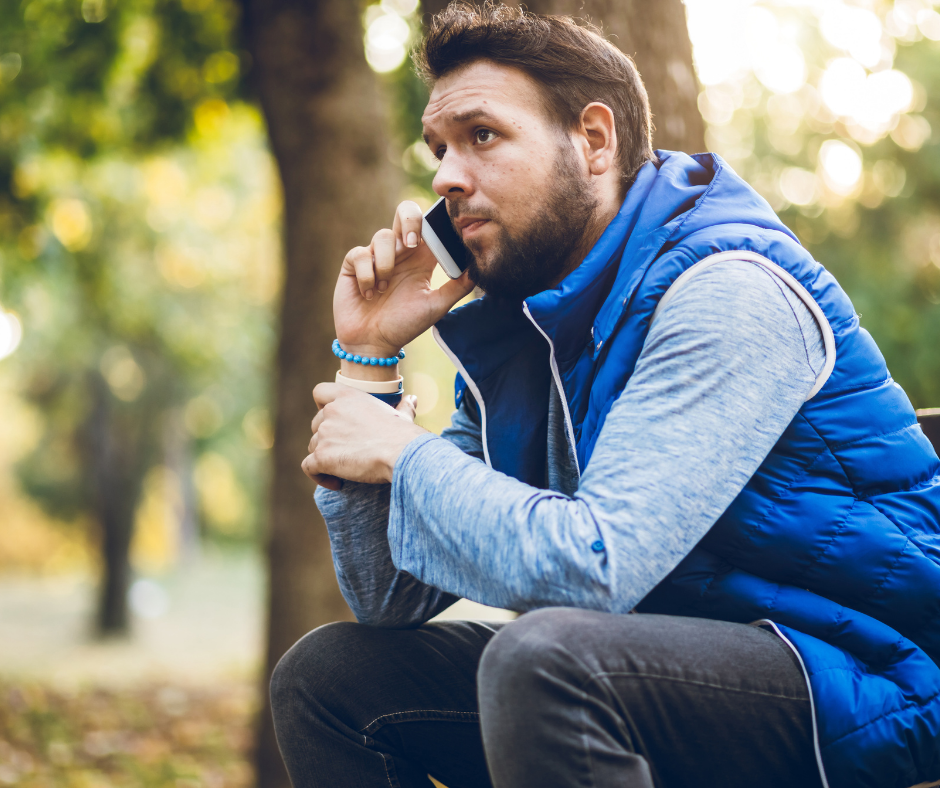 man sitting on a park bench talking on the phone, looking concerned