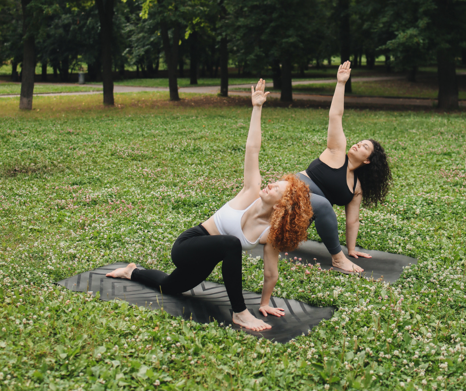 two women doing yoga in a field