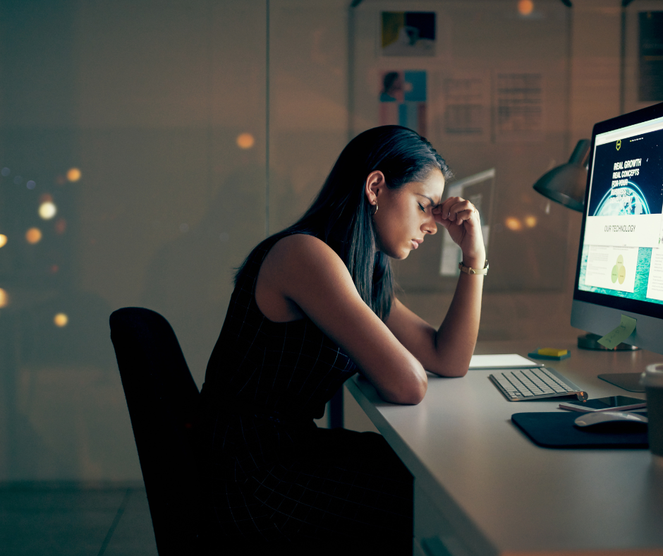 woman holding her head looking stressed in front of a computer