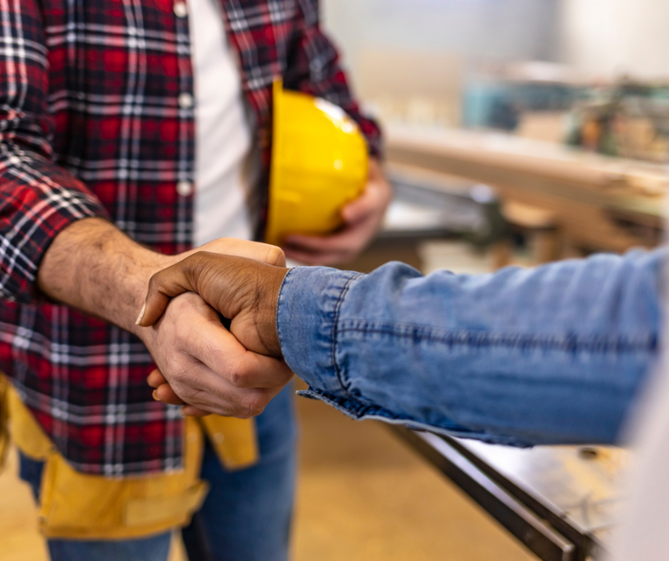 two men shaking hands, one holding a yellow hard hat