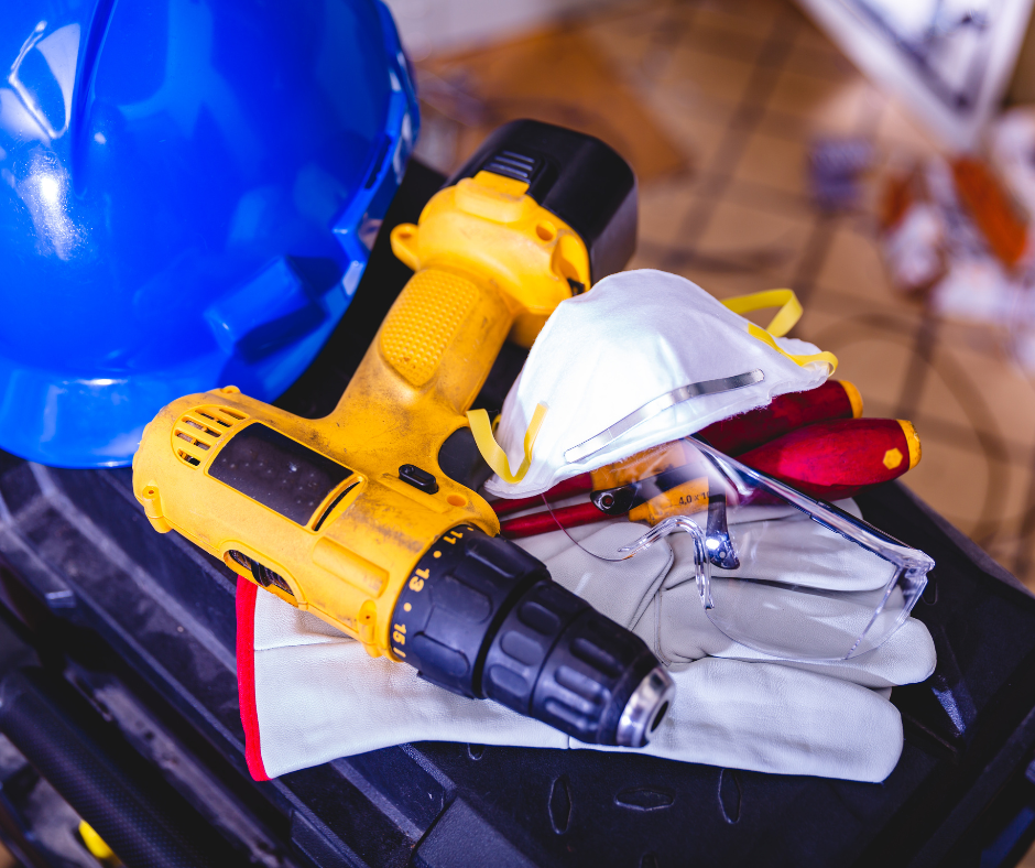 hand drill, safety helmet, gloves, face mask etc in a pile