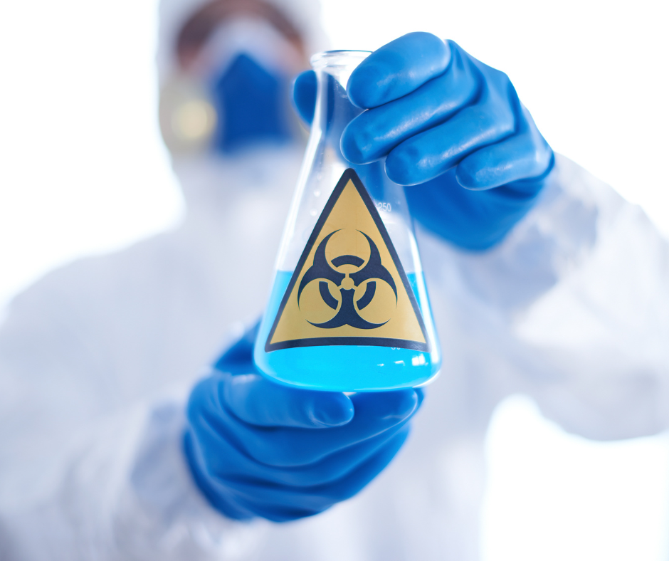 scientist holding a beaker filled with blue liquid with a warning label on it