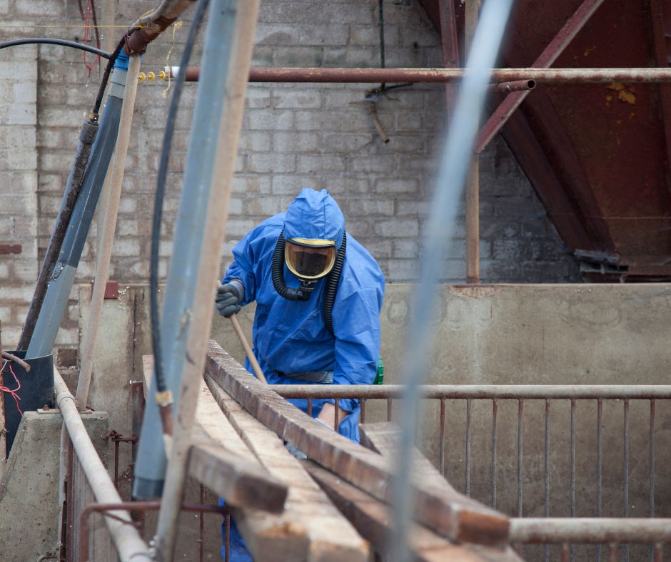 person in protective gear removing asbestos panels